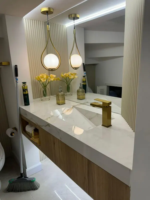 Mueble de baño flotante con mesón de piedra de vetas doradas y lavamanos integrado