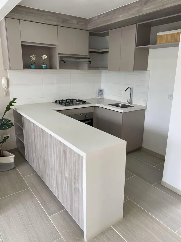 Cocina en L con mesón blanco y remate en cascada