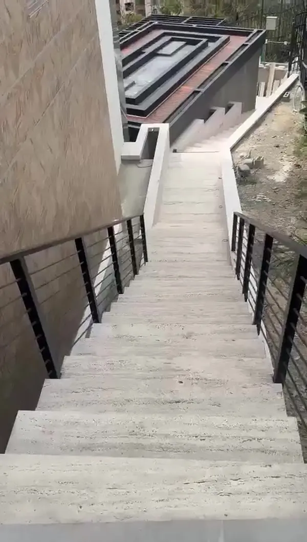 Escalera exterior revestida en piedra con baranda metálica